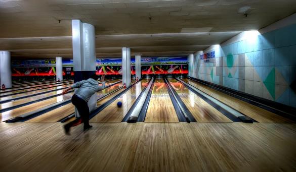 man releasing a ball while bowling at a bowling alley