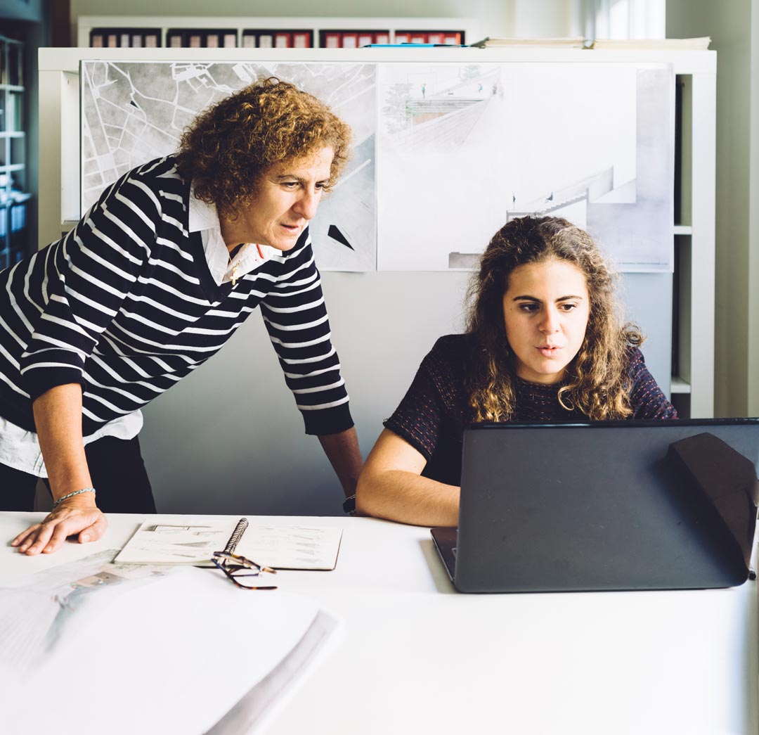 family business two women mother and daughter architects working at office with mother looking at daughter's laptop screen